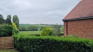Un paysage rural avec un bâtiment en briques, une clôture en bois et des champs verdoyants.