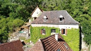 Un edificio con tetto spiovente, pareti ricoperte d'edera e una piccola finestra.