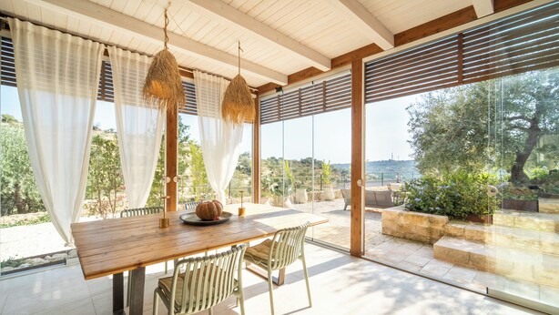 An outdoor dining area with a wooden table and chairs, a hanging light fixture, and a view of the landscape. - Azalo Country House (Avola)