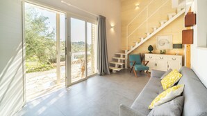 A spacious living area with a grey sofa, a teal chair, and a staircase leading to an upper level. - Azalo Country House (Avola)