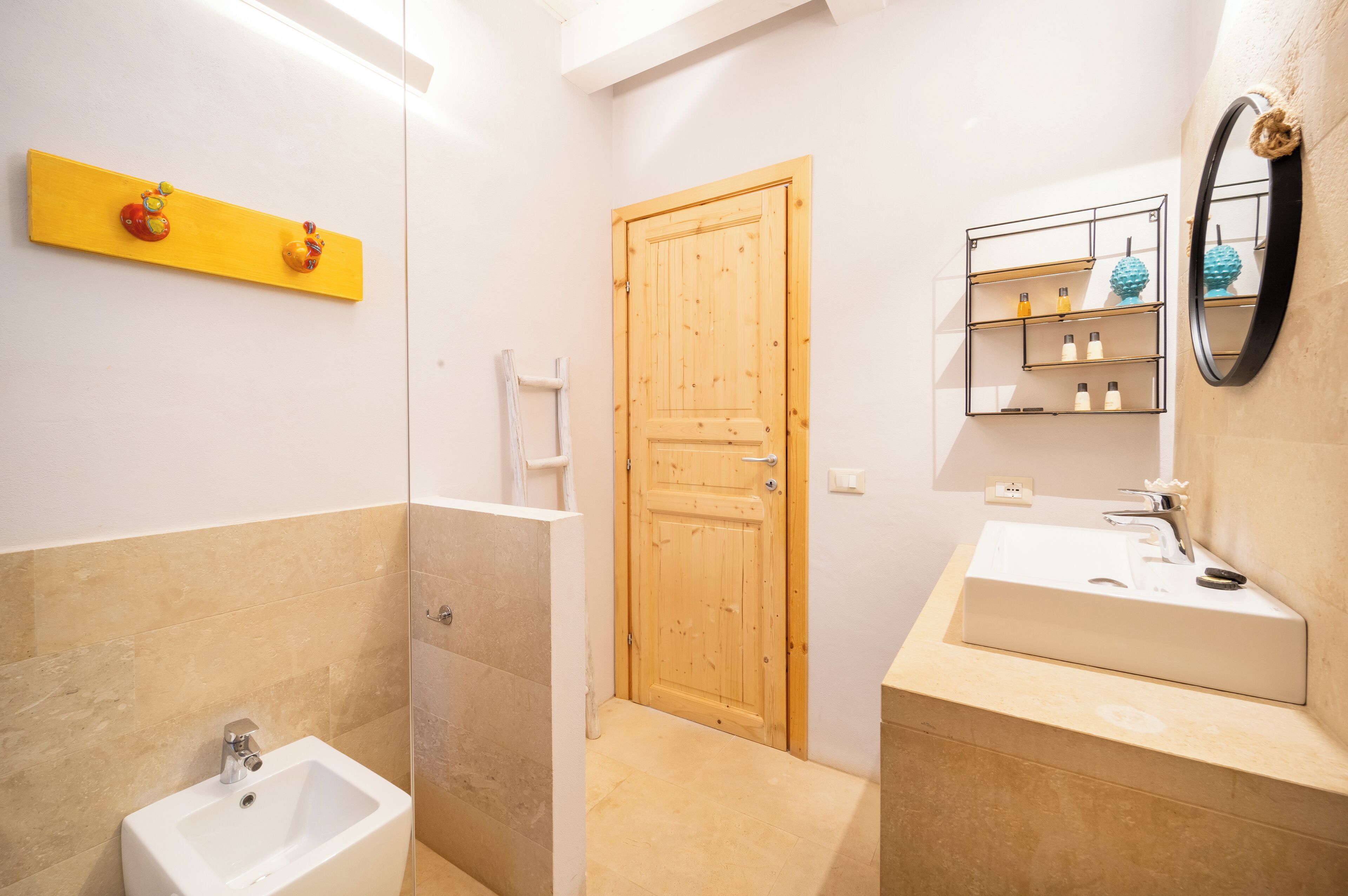A bathroom with a wooden door, a white sink, and a shelf with toiletries.