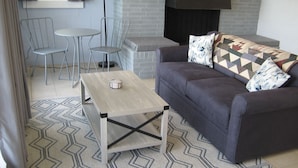 A modern living room with a grey sofa, a wooden coffee table, and two white chairs. - The "Dock House" (Edgewood)