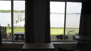 A room with a large window overlooking a lake, featuring a table and chairs. - The "Dock House" (Edgewood)