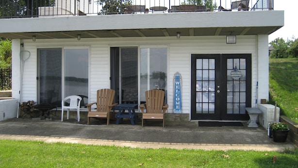 A covered porch with two wooden chairs, a small table, and a welcome sign. - The "Dock House" (Edgewood)