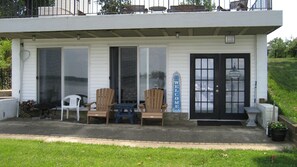 En inglasad veranda med två trästolar, ett litet bord och en välkomstskylt.