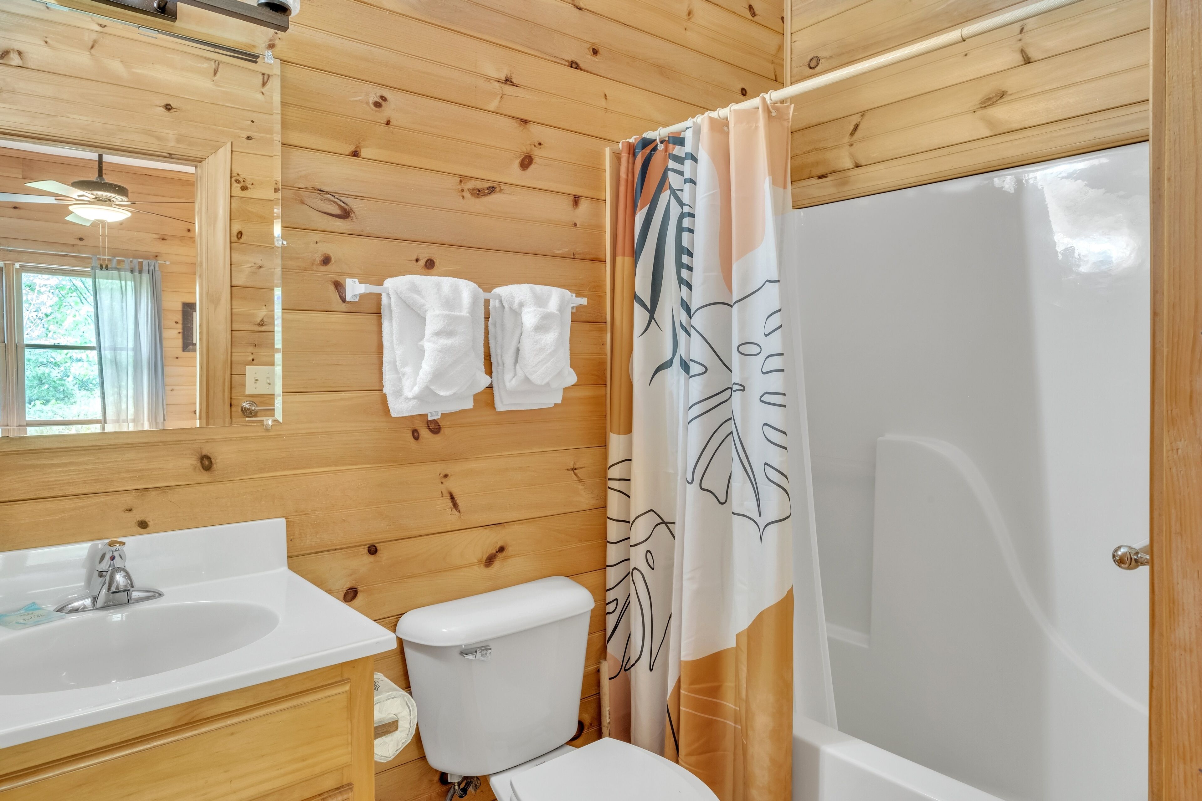 Une salle de bain aux murs lambrissés, équipée d’un lavabo, de toilettes et d’une baignoire.