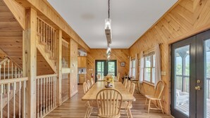 A wooden interior with a long dining table, chairs, and a staircase. - Heavenly Views - Amazing Mountain Views 8 Bedroom Cabin by Heavenly Views Resort (Gatlinburg)