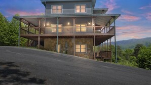 A two-story house with a balcony, stone foundation, and a view of the surrounding landscape. - Heavenly Views - Amazing Mountain Views 8 Bedroom Cabin by Heavenly Views Resort (Gatlinburg)