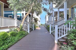A wooden pathway flanked by white railings leading to a row of buildings with balconies. - Casa de Flip Flops (Rockport)