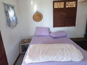 A room with a bed, a window with wooden shutters, a wall-mounted hat, and a radiator.