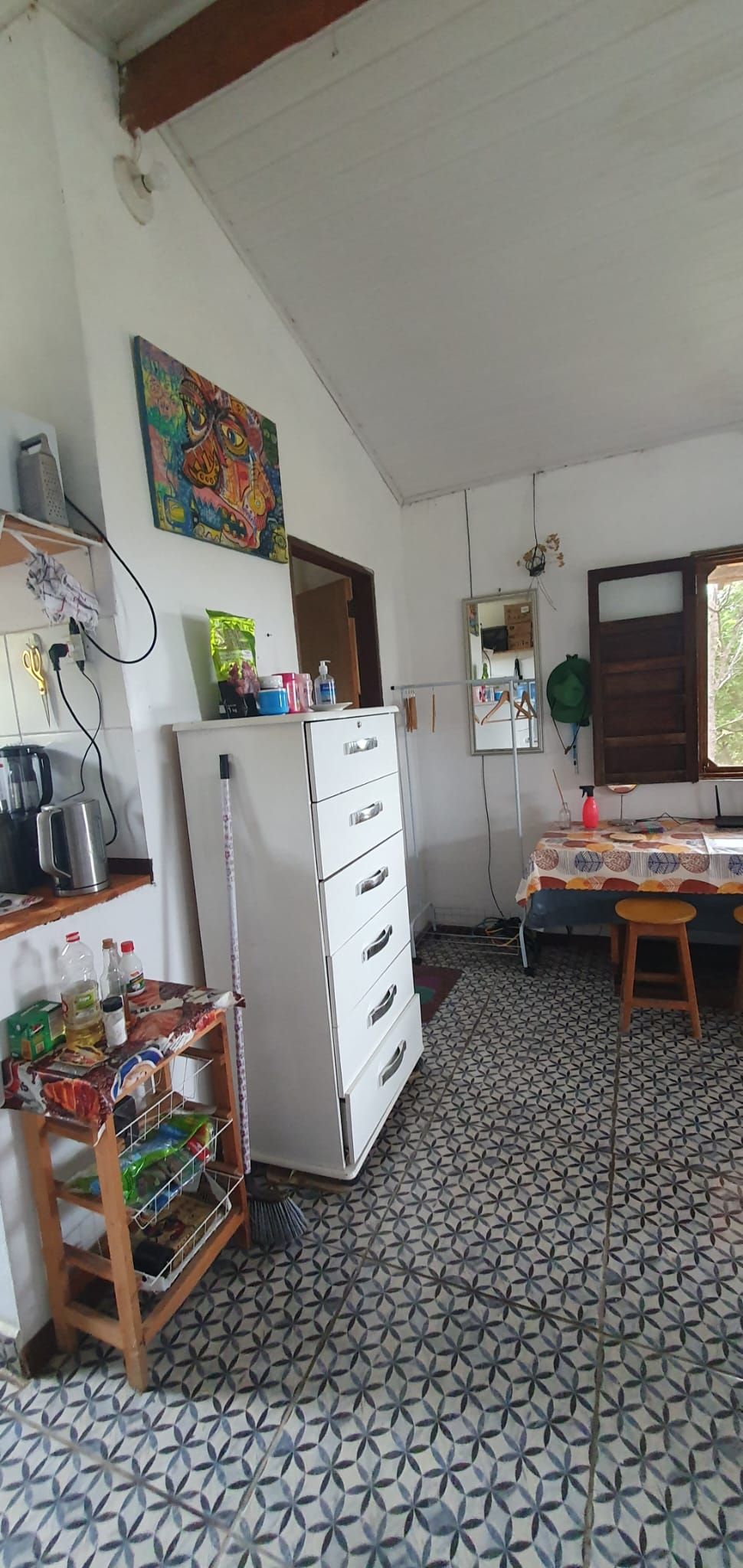 A kitchen with a refrigerator, a sink, and a tiled floor.