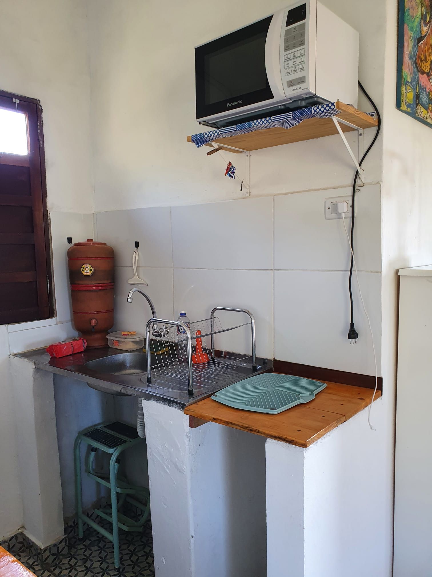 Une cuisine compacte équipée d’un évier, d’un four à micro-ondes et d’un distributeur d’eau.