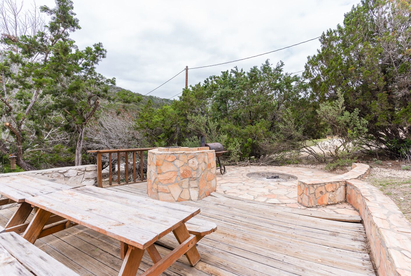 A wooden deck with stone seating and a barbecue grill.