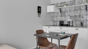 Eine moderne Küche mit weißen Schränken, einer grauen Arbeitsplatte und einer schwarzen Kaffeemaschine.