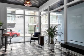A modern interior with a checkered floor, a bar area with stools, a seating area with a chair, and a large window offering a view of the street. - Swan Stylish Double Studio (Reykjavík)