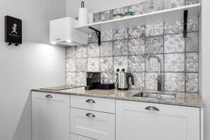 A kitchen with white cabinets, a stainless steel sink, and a patterned backsplash. - Swan Double Studio for 2 (Reykjavík)