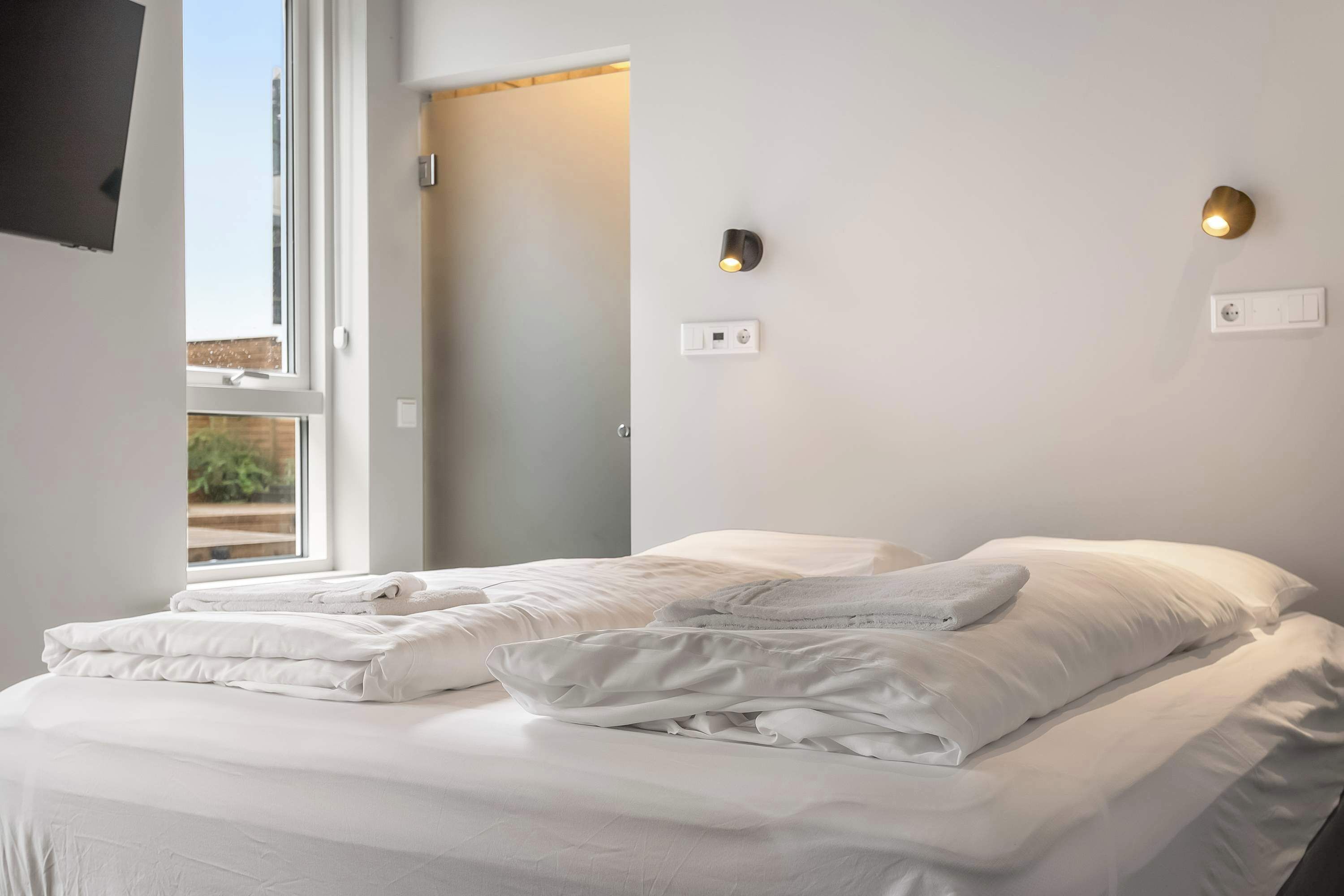 Ein Hotelzimmer mit einem Bett, zwei Wandleuchten und einem Fenster.