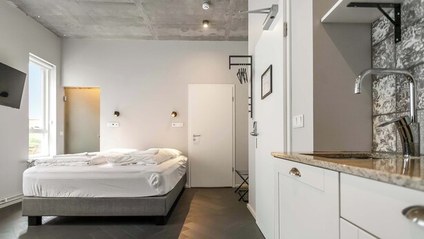 A modern bedroom with a bed, a bedside table, a wardrobe, and a bathroom with a shower. - Swan Stylish Double Studio (Reykjavík)