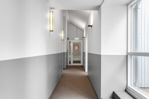 A corridor with a carpeted floor, white walls, and a door at the end. - Swan Double Studio for 2 (Reykjavík)