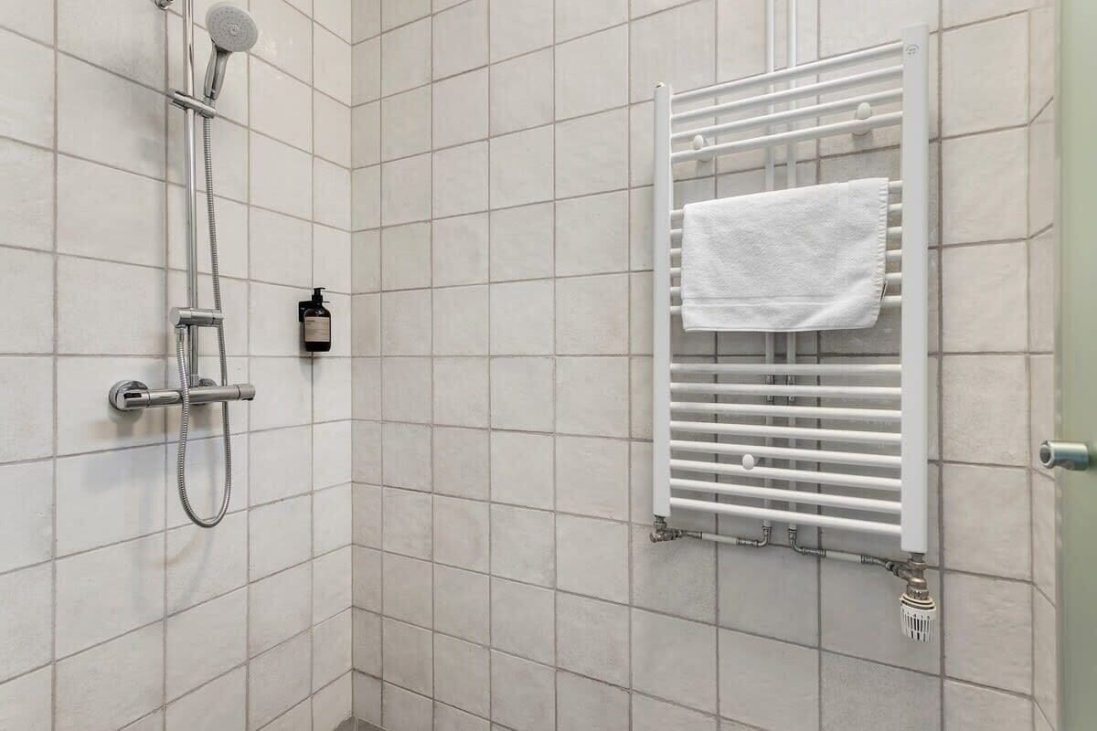 Un baño con ducha, toallero y radiador.