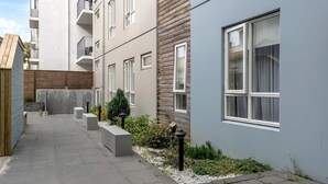 Ein modernes Wohngebäude mit einem schmalen Innenhof, Betonbänken und einem kleinen Gartenbereich.