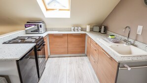 Une cuisine compacte dotée d’un puits de lumière, d’appareils électroménagers modernes et d’armoires en bois.