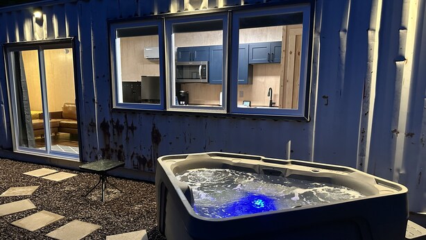 A spa area with a hot tub and a view of a kitchen through a window. - THIS IS THE ONE! SHIPPING CONTAINER CABIN-VIEW-WIFI-NATURAL BRIDGE-NADA TUNNEL (Stanton)