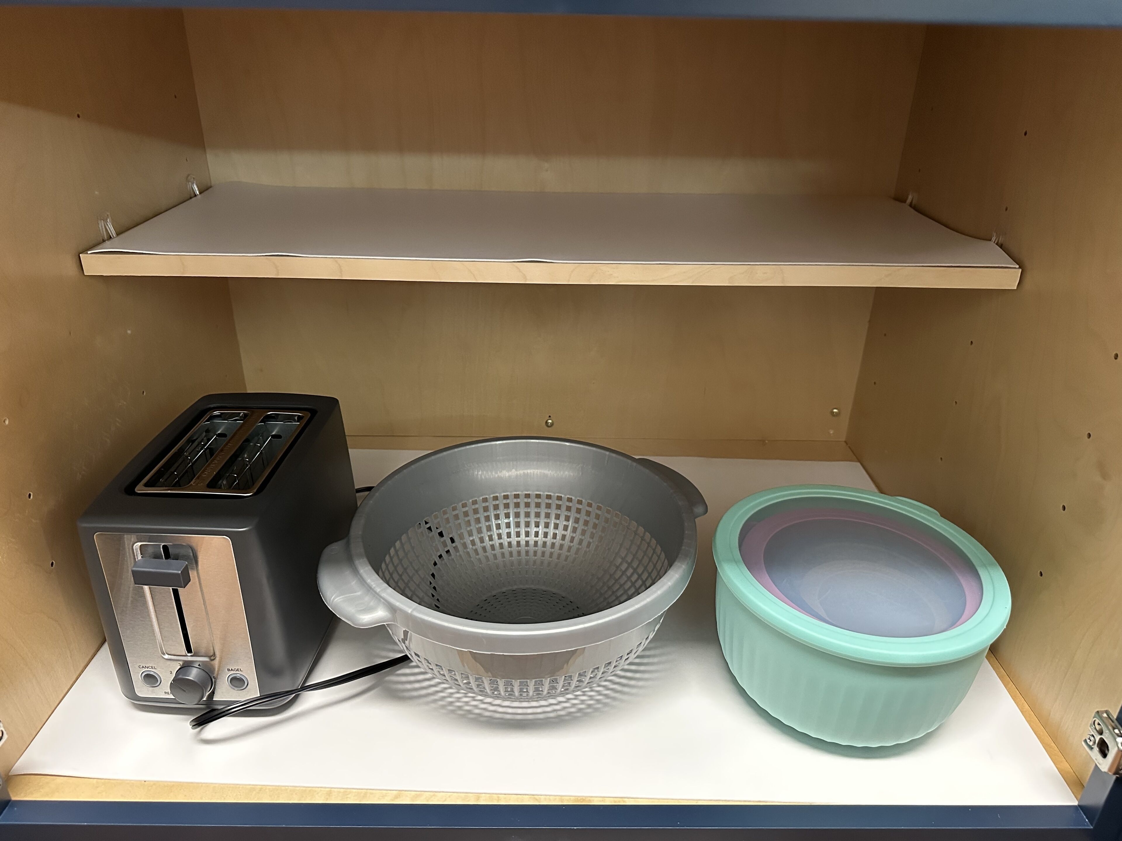 Un coin cuisine comprenant un grille-pain, une passoire et un saladier, le tout posé sur un plan de travail.