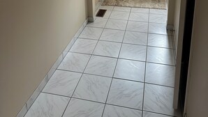 Un couloir avec une porte blanche, un tableau encadré accroché au mur et un tapis à motifs menant à la porte.