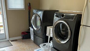 Une buanderie équipée de deux machines à laver à chargement frontal et d’un réfrigérateur.