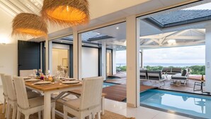 A modern dining area with a poolside view. - Superbe Villa vue mer (Sainte Anne)