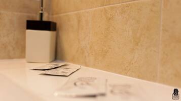 A bathroom with beige tiles, a white sink, and a soap dispenser.