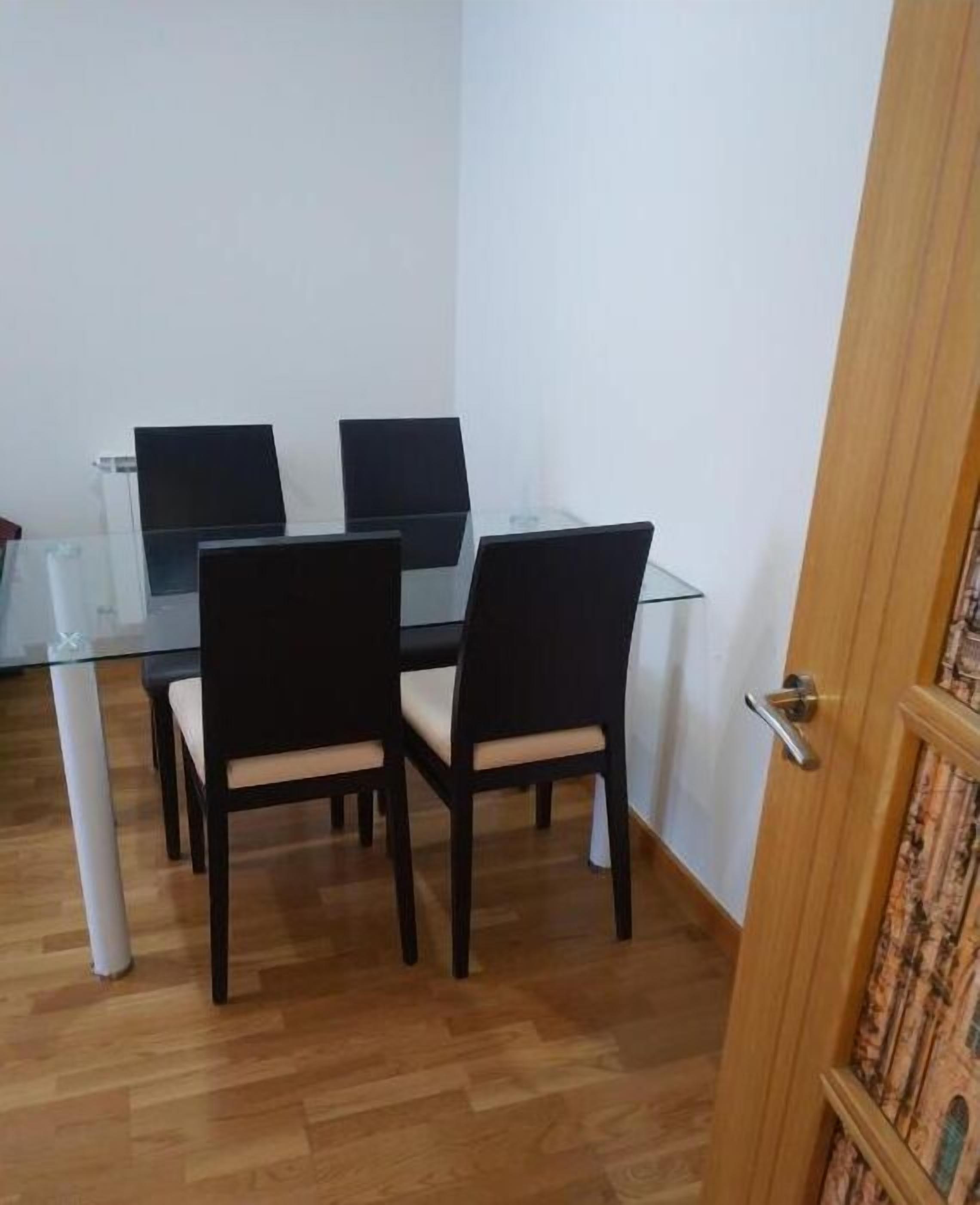 Een eetgedeelte met een glazen tafel en vier stoelen.