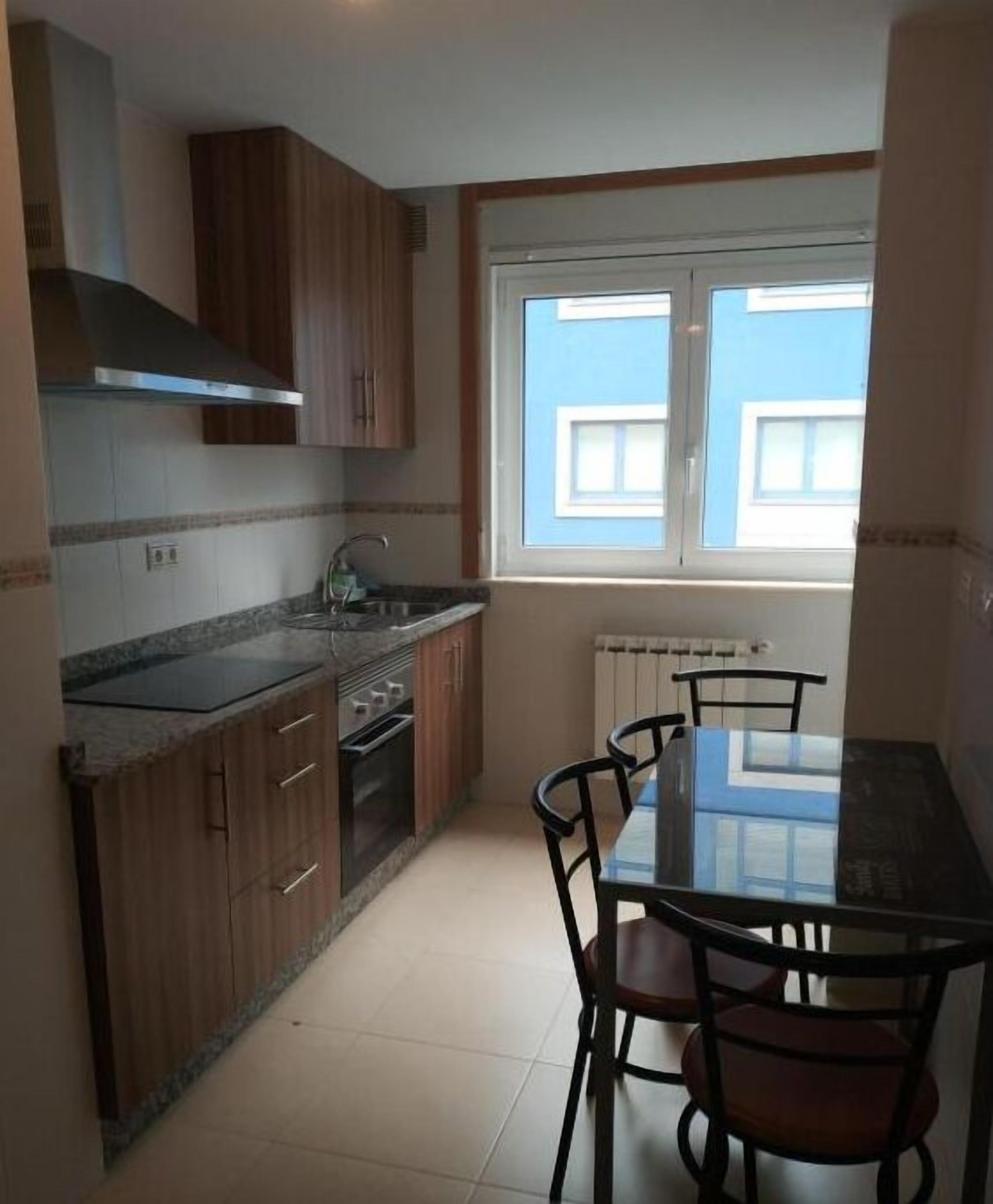 Une cuisine compacte avec des meubles en bois, un four encastré et une table à manger avec des chaises.