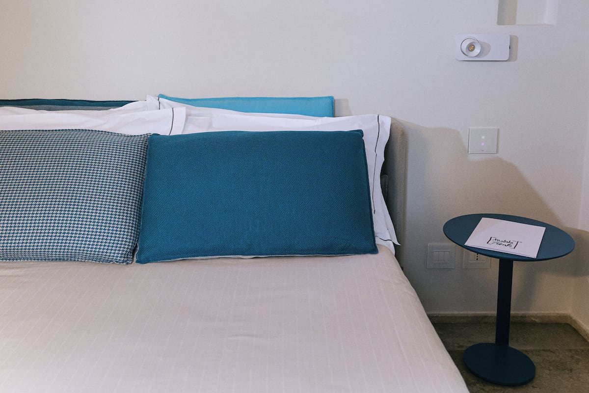 Habitació d'hotel amb llit, almoines, una taula petita i obra d'art penjada a la paret.