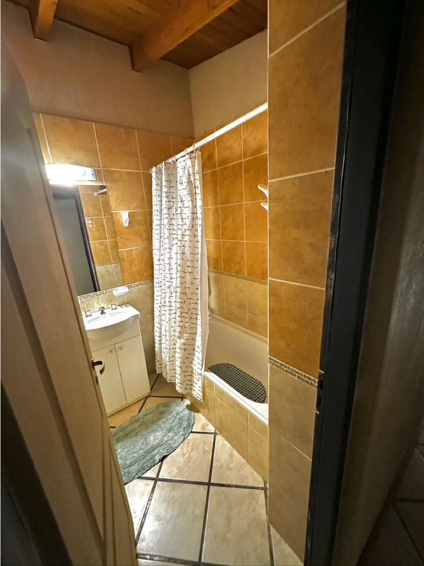A bathroom with a shower, sink, and tiled floor.