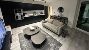 Una cocina moderna con armarios negros, un comedor con mesa y sillas, un sofá y un televisor.