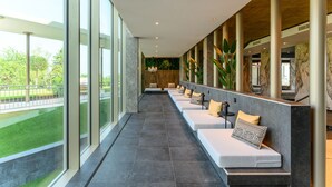 A modern hotel lobby with a long bench seating area, large windows, and a view of the outdoors. - Hotel Vinifera Wine & Spa (Balatonfured)
