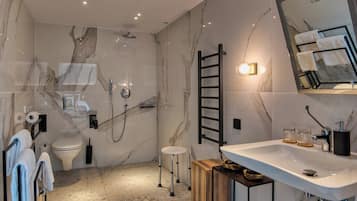 A modern bathroom with a marble floor, a shower, a toilet, a sink, and a mirror.