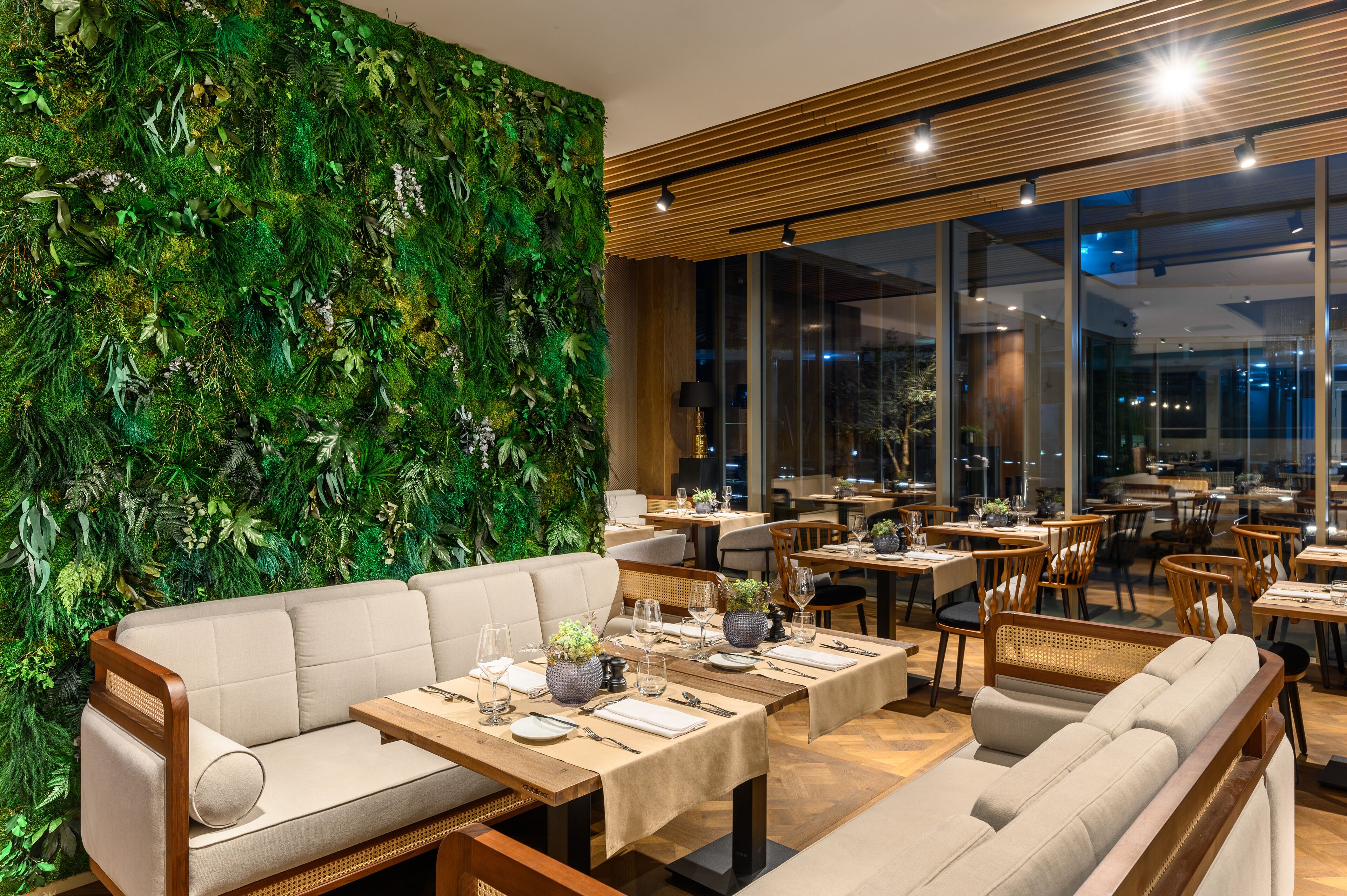 Ein Restaurant mit grüner Wand, Holzboden und mehreren Tischen mit Stühlen.