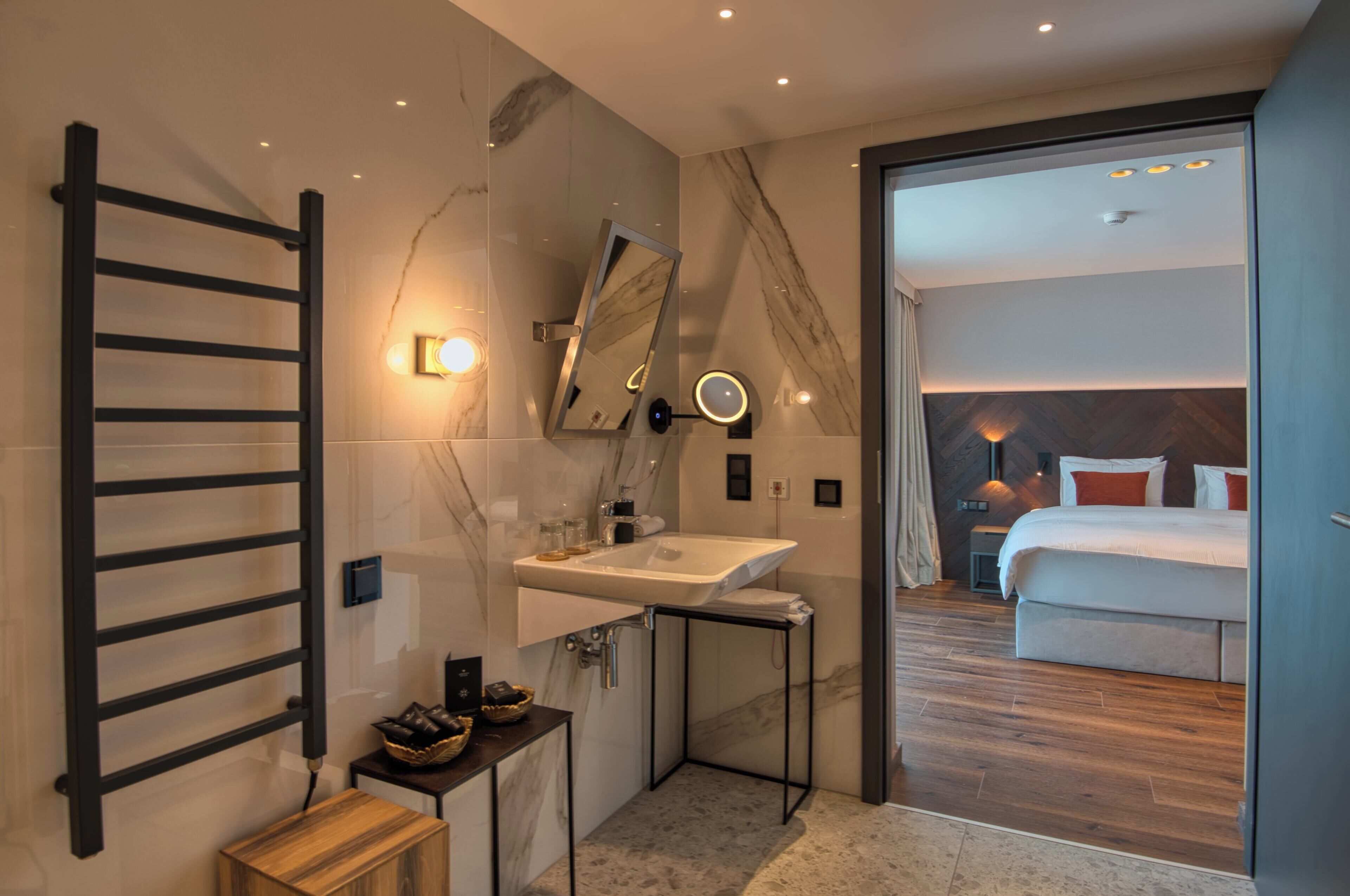 A modern bathroom with a towel rack, sink, mirror, and lighting.