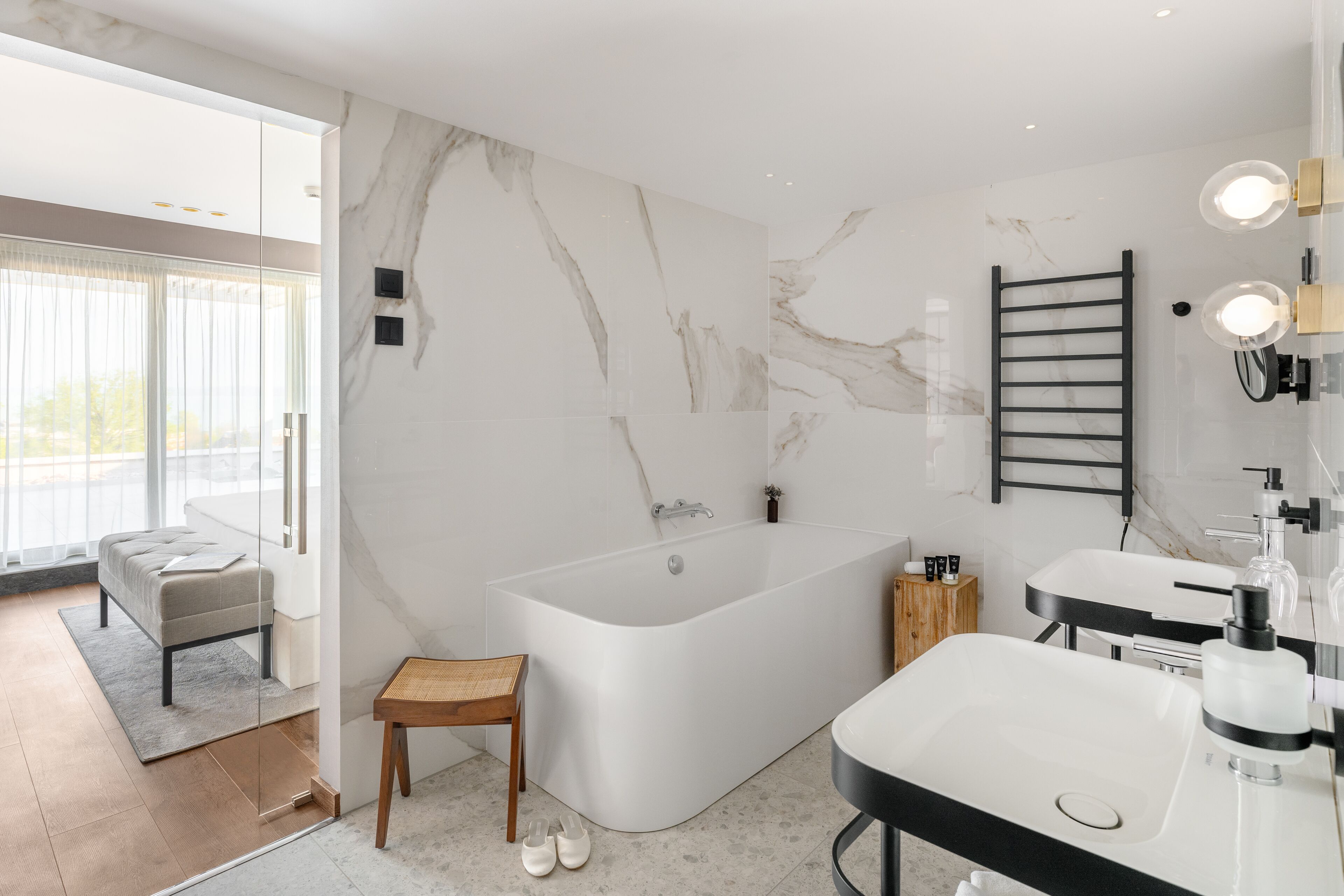 Un baño moderno con una bañera independiente, un tocador con espejo y un perchero para toallas.