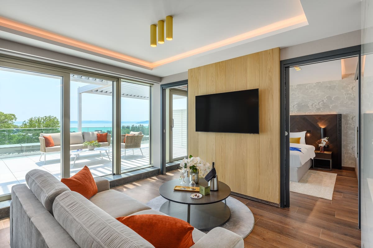 A modern living room with a large sofa, a coffee table, and a flat-screen TV mounted on the wall.