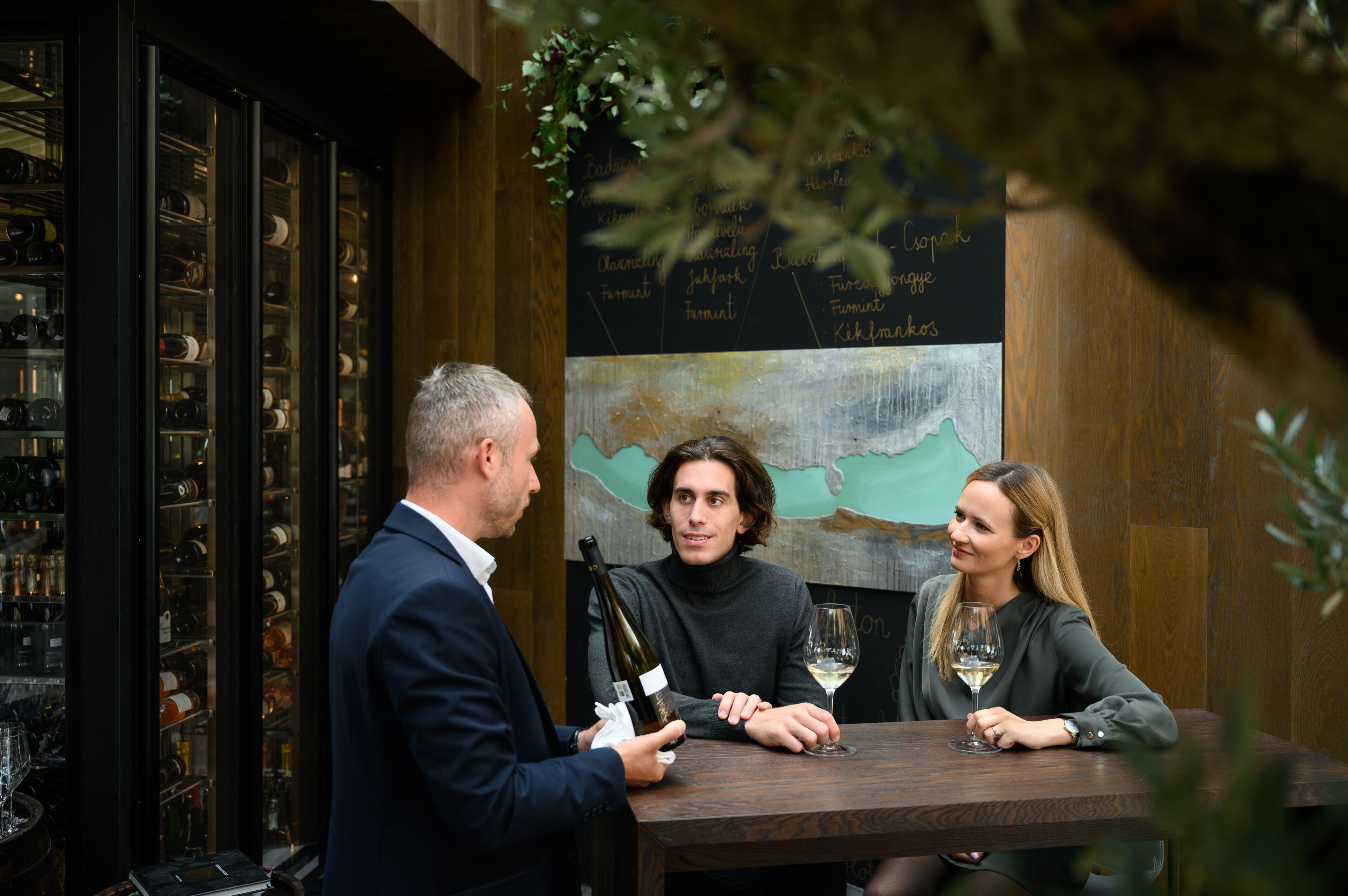 A wine tasting event with a wooden table, wine bottles, and glasses.