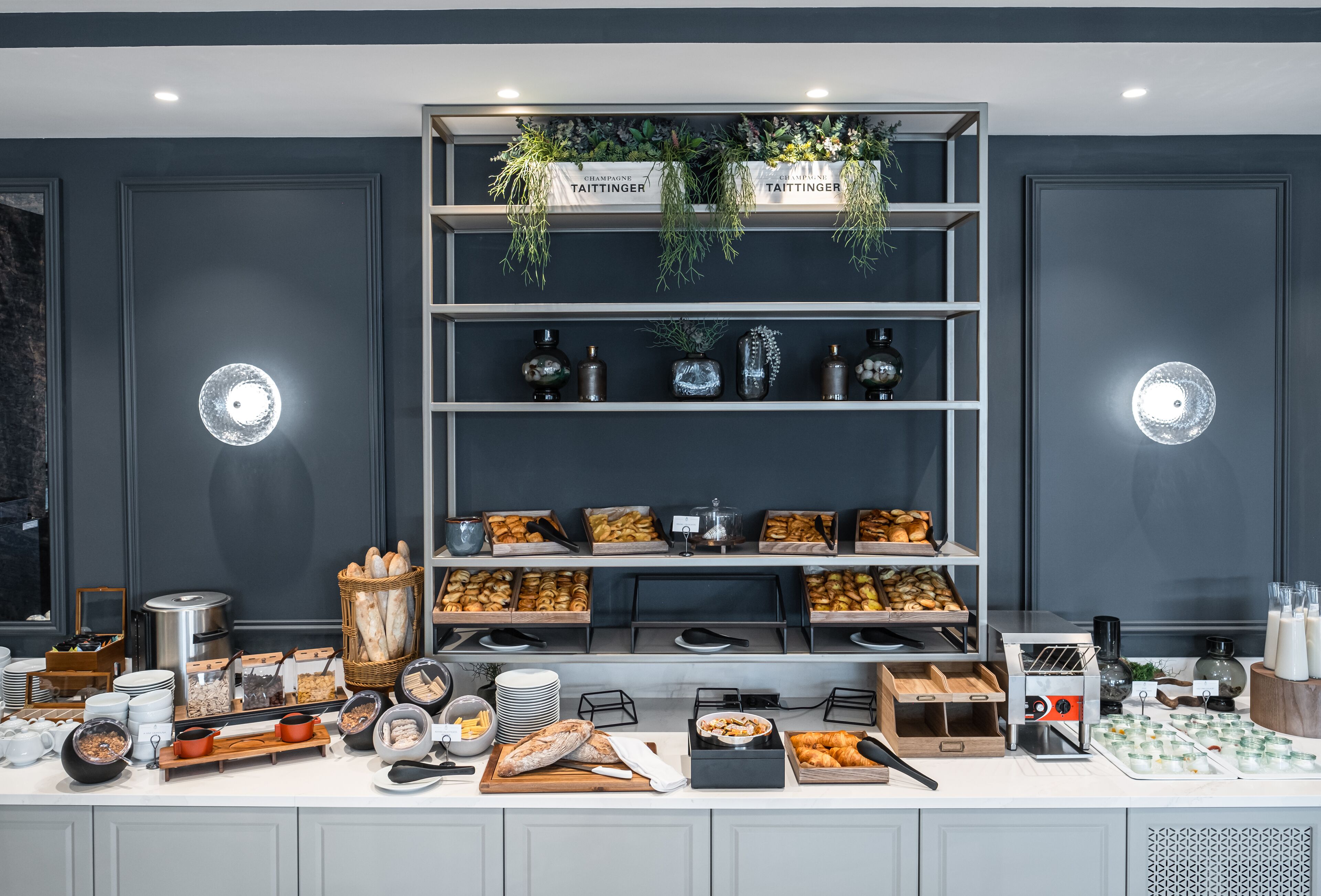 A buffet setup with various food items and beverages, including bread, pastries, and a coffee machine.