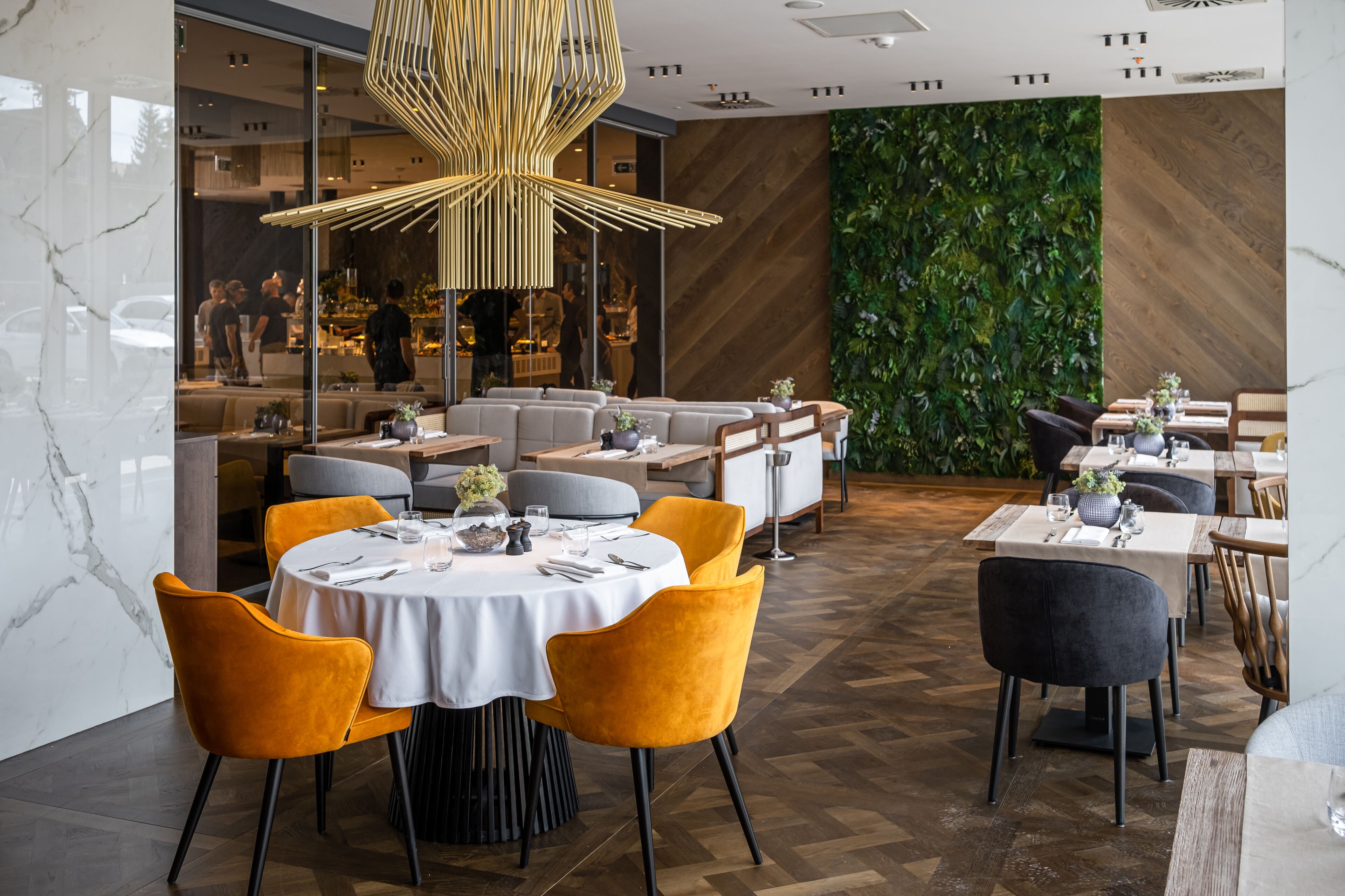 A modern restaurant with round tables, yellow chairs, and a unique ceiling light fixture.