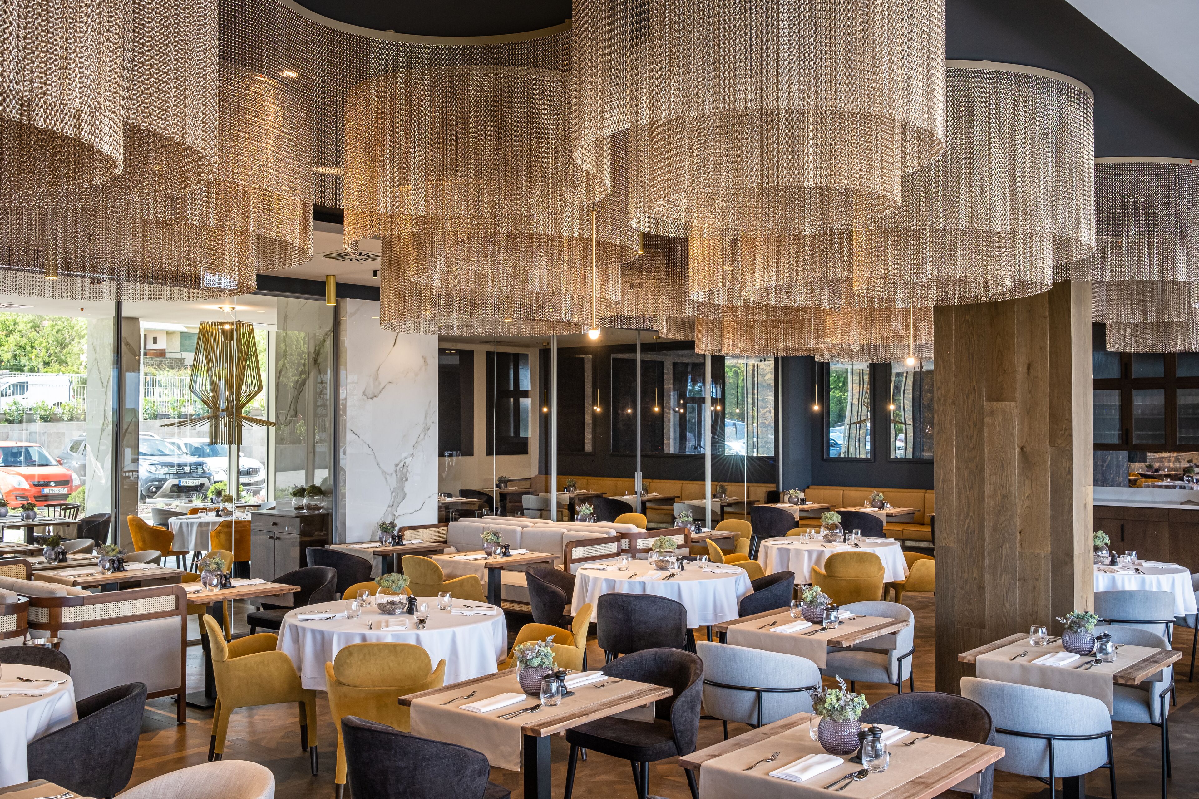 Un interior de restaurante moderno con mesas redondas, asientos cómodos e iluminación decorativa colgante.