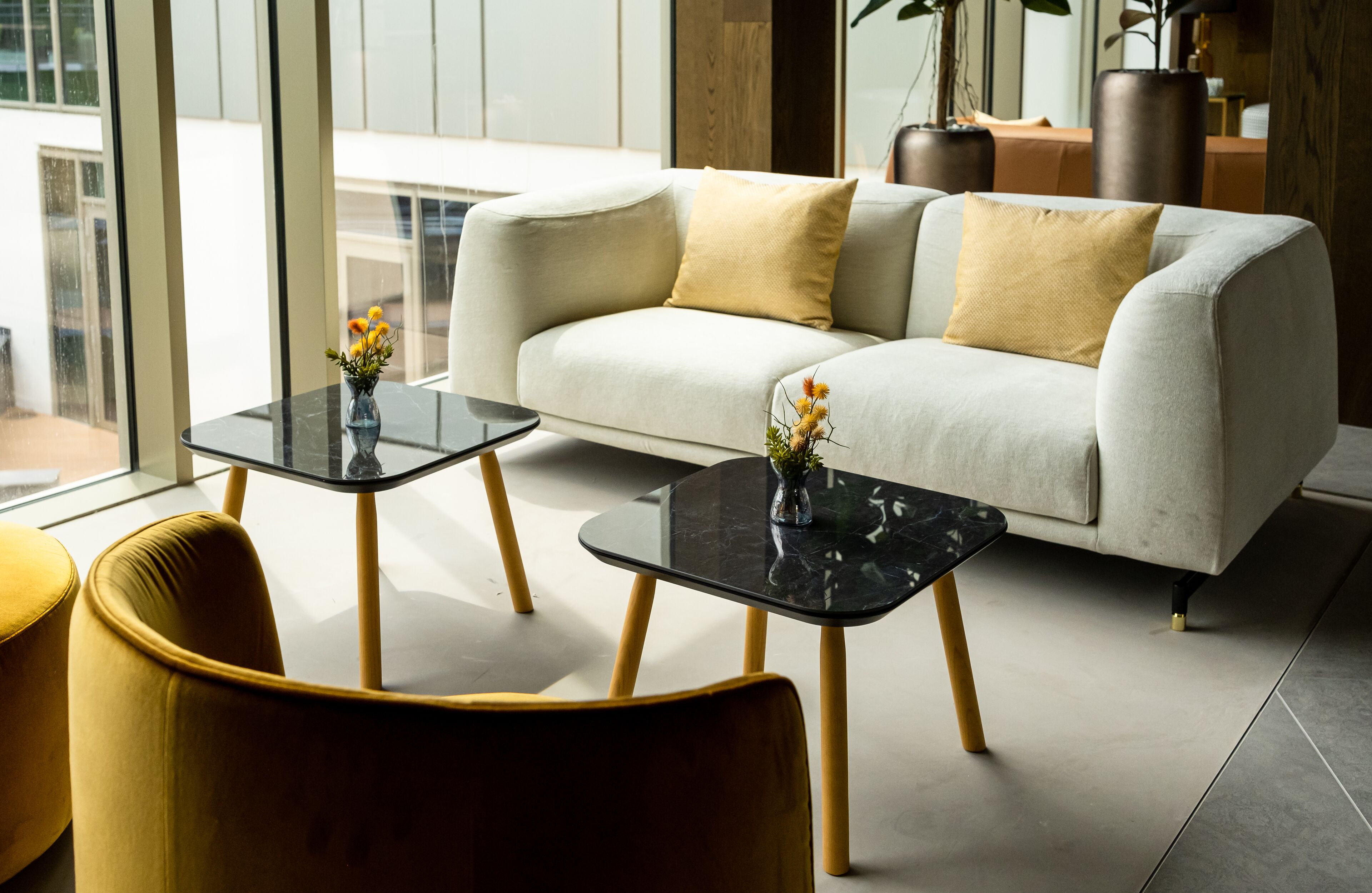A modern living room with a sofa, two side tables, and a yellow armchair.
