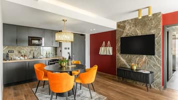 Una cocina moderna con armarios oscuros, una isla central y una zona de comedor con sillas color naranja.
