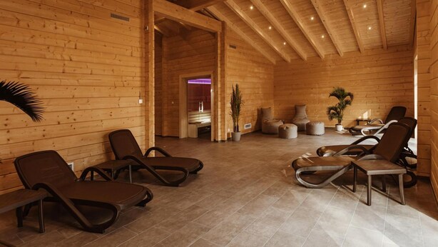 A wooden interior with lounge chairs and a massage table, suggesting a spa or relaxation area.